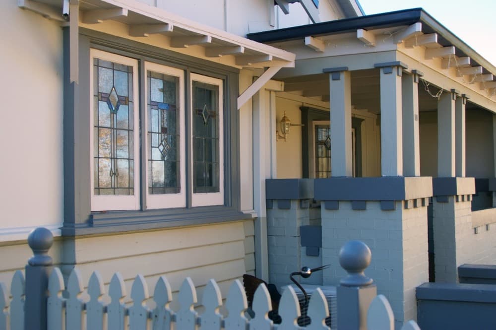 Californian bungalow in Orange NSW repainted by Murrays Painting, cream weatherboards with blue-grey trim, leadlight windows and a painted picket fence